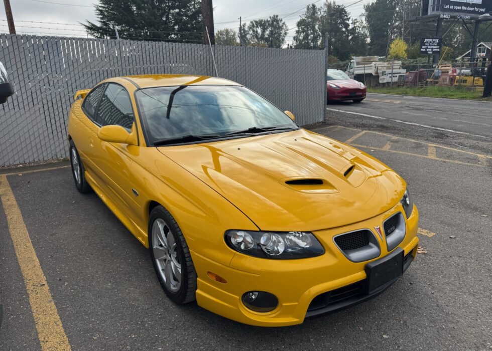 Front three-quarter view of a yellow Pontiac GTO with a fresh high-gloss paint job and clear headlights at D&R Auto Body & Paint.