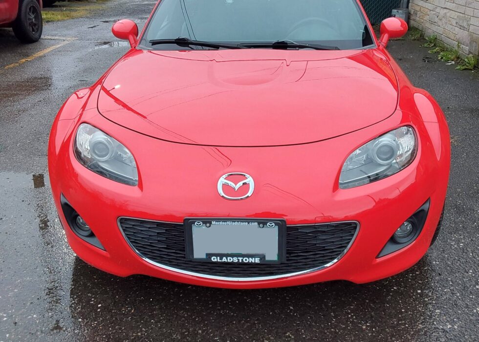 Close-up front view of a vibrant red Mazda MX-5 Miata featuring a high-gloss finish and clear headlights at D&R Auto Body & Paint.